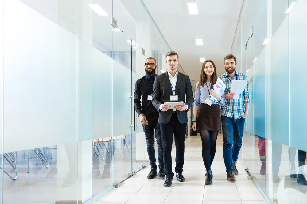 Full length of group of happy young business people walking the corridor in office together